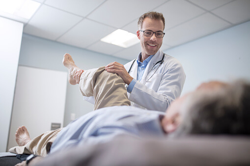 Image of a patient laying on a table and a doctor lifting the patient's leg.